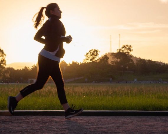 Woman running on track at sunset.